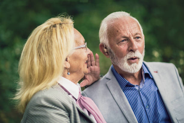 istock Senior couple with a hearing problem sitting on bench outdoor 1418963073