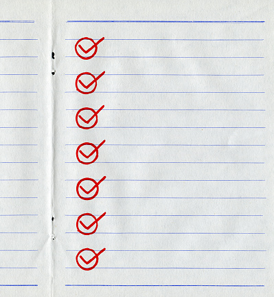 A person's hand taking notes on a checklist