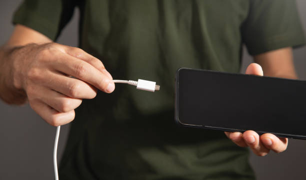 istock Man connecting charger cable to mobile phone. 1418965511