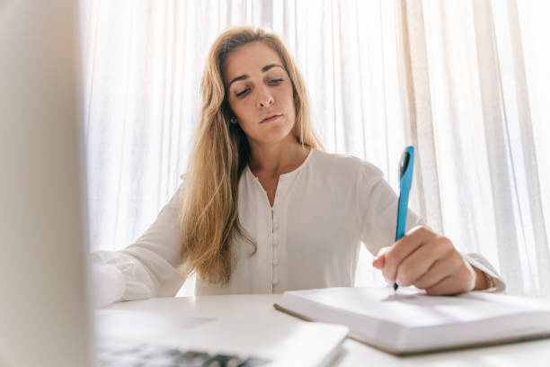 istock Serious freelancer writing in diary and using laptop on desk 1418967854