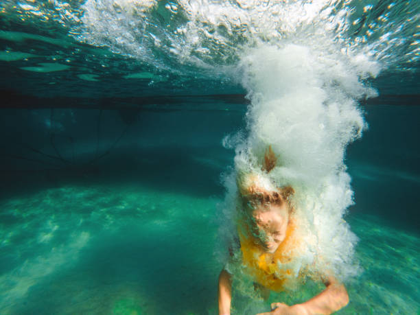 istock Young Caucasian Boy Jumping Into Clear Water, Wearing A Life Jacket 1418969559