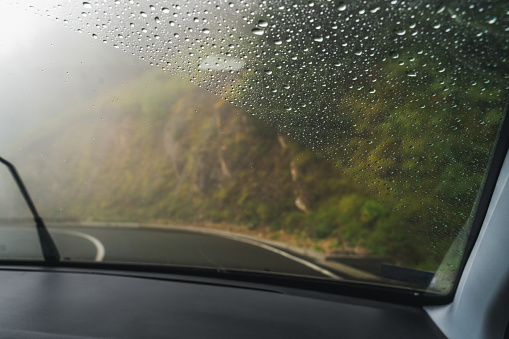 View from the car, windshield with raindrops. View of the road in the forest