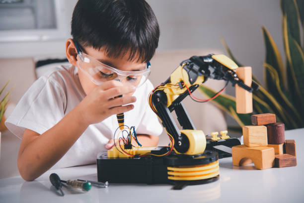 istock Happy Asian little kid boy using screwdriver to fixes screws robotic machine arm in home workshop 1418976232