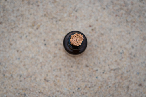 Top view of small brown medicine bottle cork on beige sand background. Empty copy space.