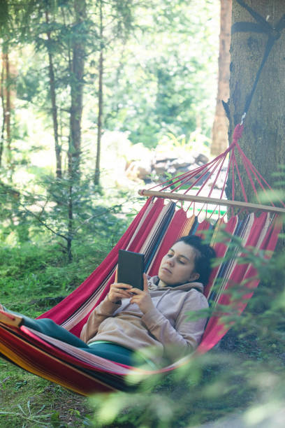 istock woman laying down in hammock reading book 1418980447