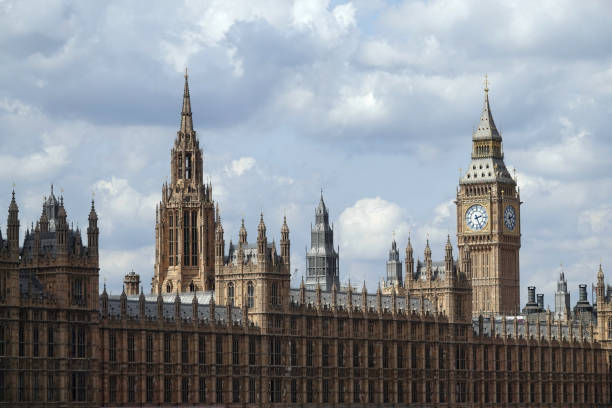 the houses of parliament and big ben under a cloudy sky in london, uk. - crane skyline uk tower of london imagens e fotografias de stock