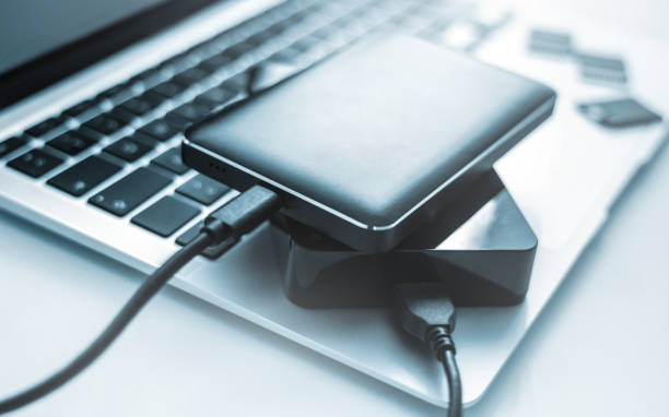 istock Laptop computer with external hard drives and memory cards data is transferred and backed up 1418986036