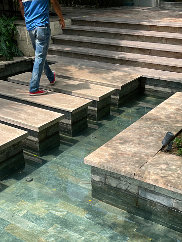 Stock photo showing a row of stepping stones that are being used to cross a large formal pond in a public garden.