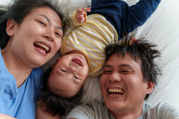 istock Happy Asian family taking selfie while lying on bed together 1418993709