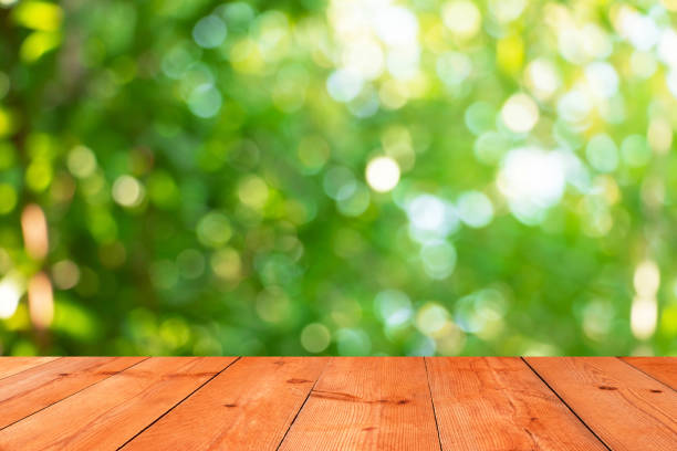 istock perspective wooden board over blurred leaves bokeh 1418995689