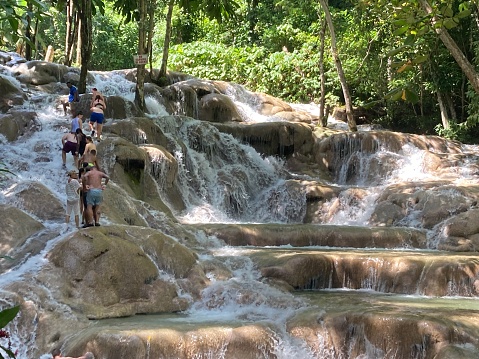 Siquijor, the Philippines - 12 Mar 2020: Boy jumping with tarzan rope over waterfall. Rope swing jump into waterfall. South Asia ecotourism and adventure. Young traveler on gap year. Extreme sport