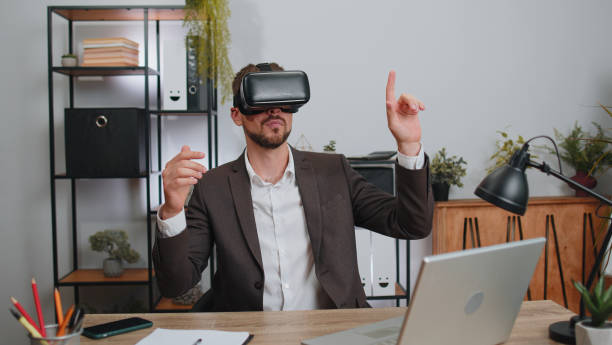 istock Businessman working using virtual reality futuristic technology VR app headset helmet at home office 1418997130