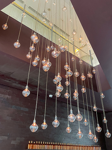 Stock photo showing lit translucent glass sphere lantern lights hanging displayed from a ceiling on cables of varying length.