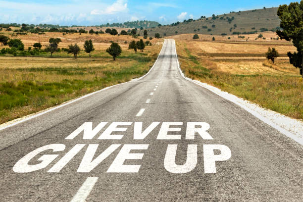 istock Never Give Up Word on Asphalt Road 1418999245