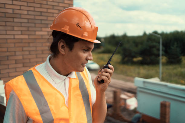 istock Foreman inspector or construction worker in hardhat portrait. Engineer in helmet with walkie-talkie in hand directs construction process 1418999436