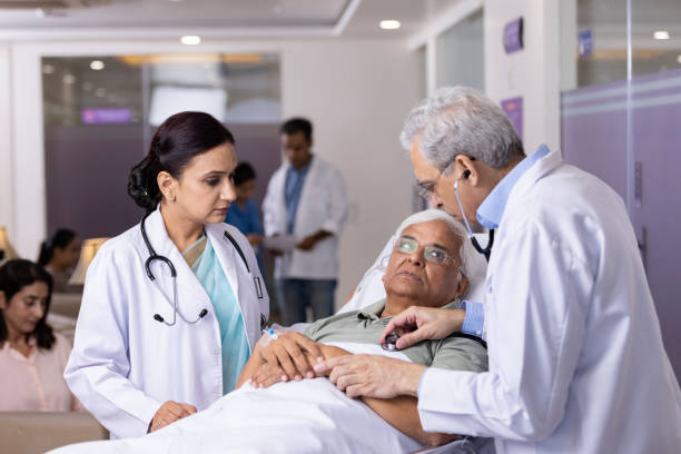 Doctors checking heartbeat of patient using stethoscope Doctors checking heartbeat of patient using stethoscope lying on hospital bed elderly stock pictures, royalty-free photos & images