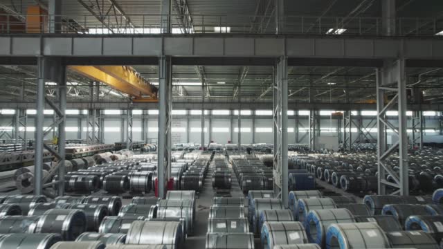 Industrial warehouse of a metallurgical enterprise. Rolled metal products are stored in rows in a warehouse.