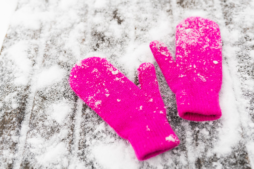 Pink mittens on white snow, top view. Winter outdoor games