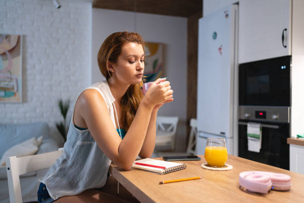 istock Young woman, sitting for a kitchen counter, and drinking coffee 1419011433