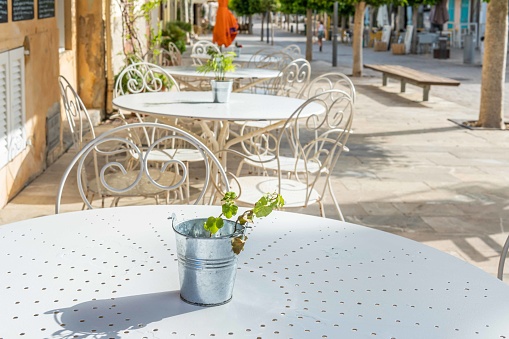 Close-up of vintage tables and chairs on the terrace of a coffee shop with no customers. Mallorca island, Spain