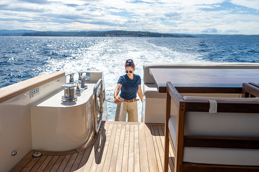 Woman stewardess spraying shower while standing on luxury yacht.