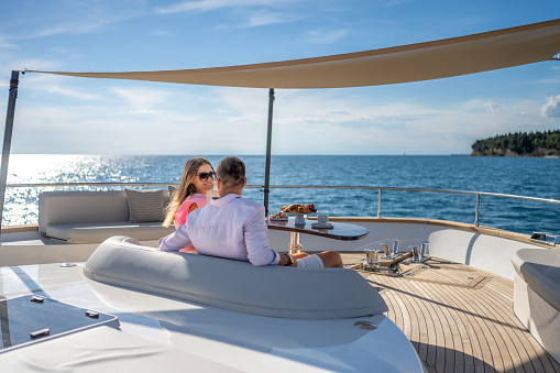 Couple looking at each other while sitting on sofa on luxury yacht.