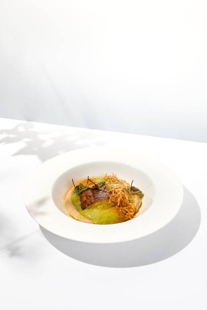 istock Roasted fish with crispy skin, celery cream and fresh herbs espuma. Fried halibut fillet on mashed celery and crunchy potatoes. Roasted fish fillet in elegant restaurant menu 1419017828