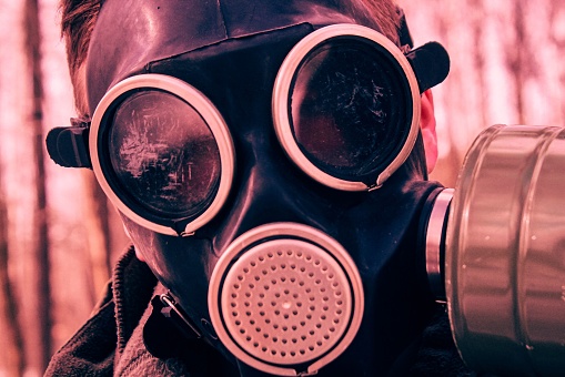 A closeup of a gas mask over a blurry background of trees