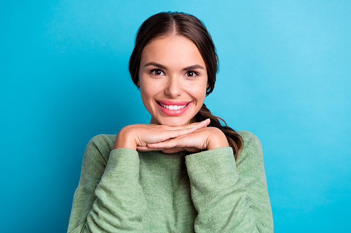 Photo of pretty positive person hands under chin beaming smile isolated on blue color background.
