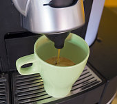 Close-up of espresso lungo pouring from coffee machine in a green ceramic cup