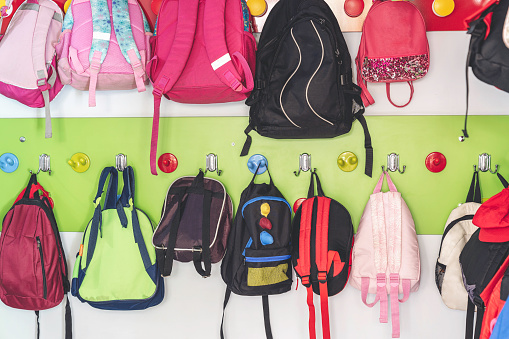 School backpacks hanging on a wall rack. Indoors of preschool building
