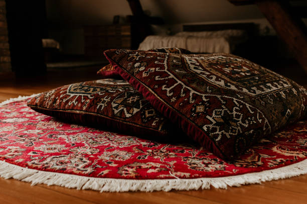 deux oreillers de lit persans rouges sur un tapis rond tricoté à la main sur le sol. - carpet rug persian rug persian culture photos et images de collection