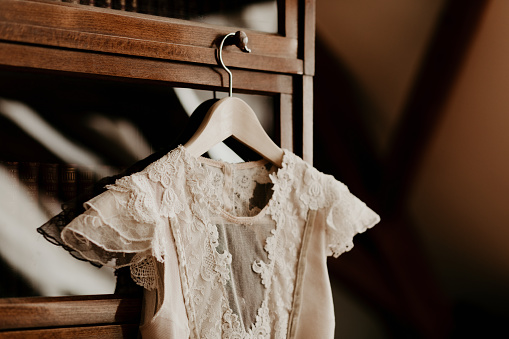 Wedding preparation image, with white beige lace dress on a vintage wooden hanger.