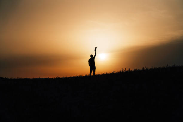 Silhouette of a photographer at sunset. He's holding his camera. Copy space.