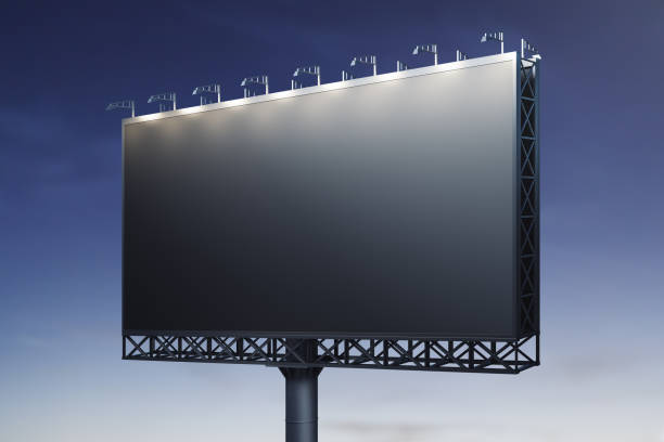 istock Blank black billboard on blue sky background at night, front view. Mock up, advertising concept 1419026068