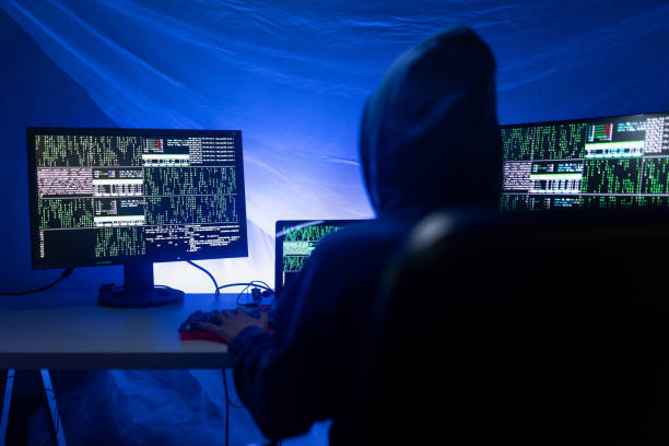 istock Rear view od hooded hacker by computer in the dark room at night, cyberwar concept. 1419026847