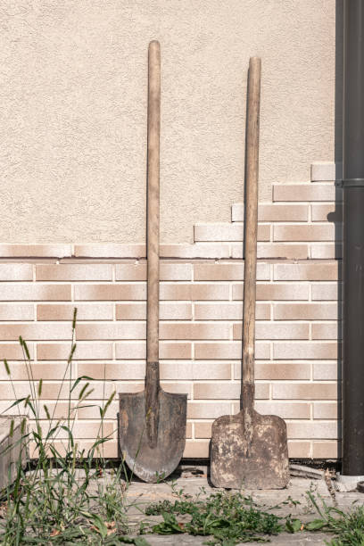 Two dirty filthy shovels against the tile wall summer day, spade