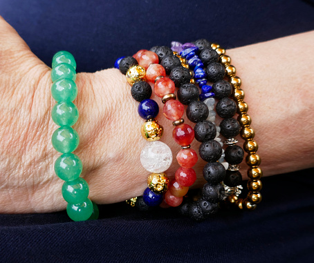 Arm of an elderly woman with lots of lava stone and semiprecious gemstone bracelets