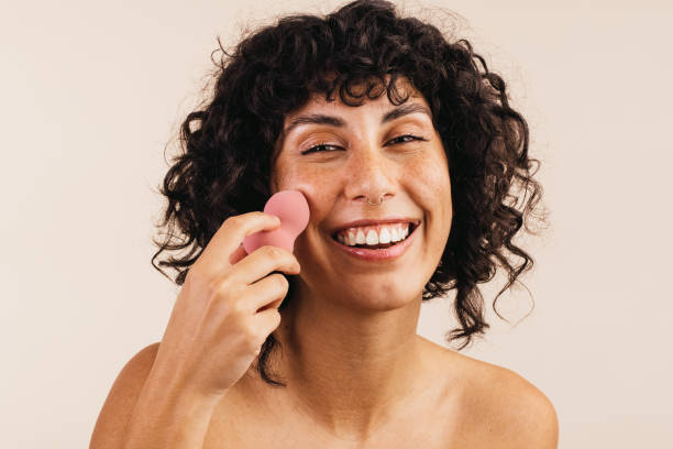 istock Cheerful woman using a makeup sponge on her face 1419037408