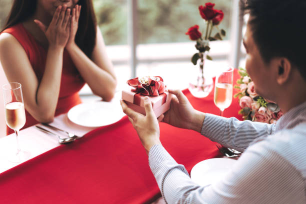 istock Man couple hand hold a romantic present red gift box give it to girlfriend. 1419038367