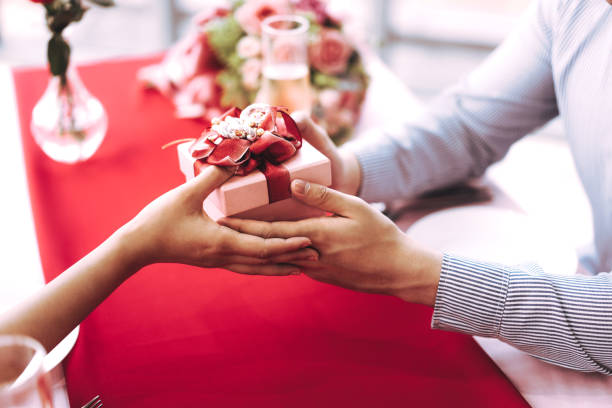 istock Man couple hand hold a romantic present red gift box give it to girlfriend. 1419038409
