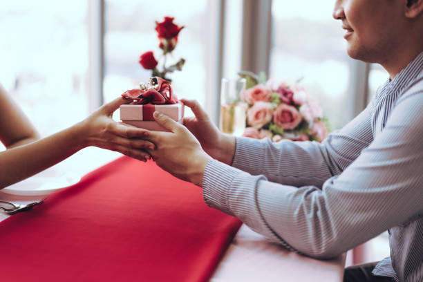 istock Man couple hand hold a romantic present red gift box give it to girlfriend. 1419038519