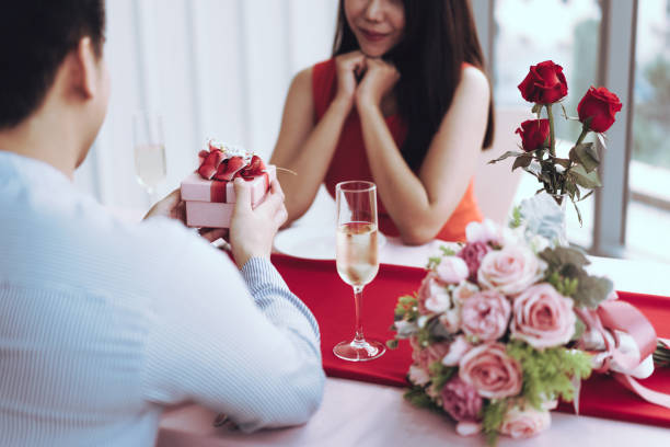 istock Man couple hand hold a romantic present red gift box give it to girlfriend. 1419038522