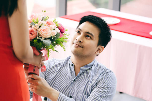 istock Asian couple with flower bouquet at dinner table on anniversary. 1419039180