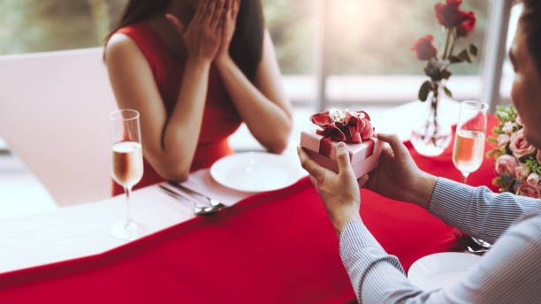istock Man couple hand hold a romantic present red gift box give it to girlfriend. 1419039312
