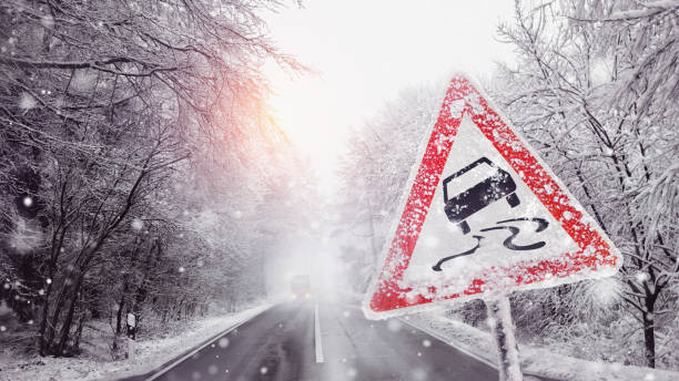 señal de advertencia debido al hielo negro en la carretera nevada - road ice danger winter fotografías e imágenes de stock