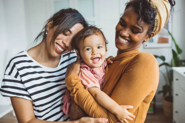 Young mothers playing with baby girl in living room.