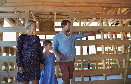A young family on site inside new home construction framing.