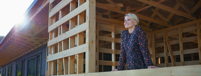 A young woman on site inside construction framing dreaming of her new home.