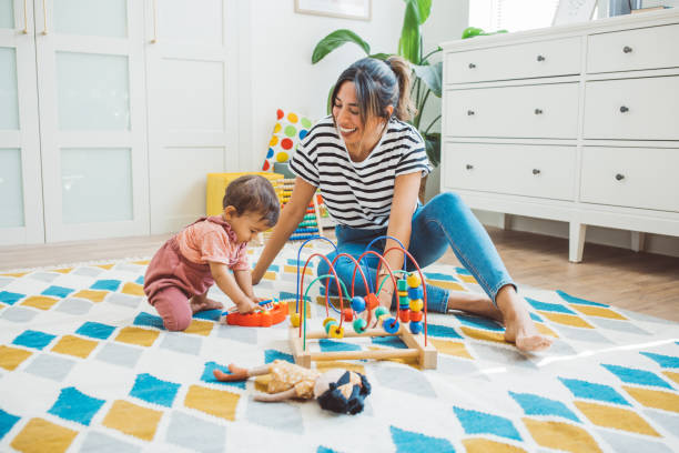 Young mother with baby at home Young mother playing with baby girl in living room. day in the life stock pictures, royalty-free photos & images